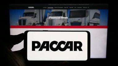 Stuttgart, Almanya - 08-06-2023: ABD 'li ticari araç şirketi PACCAR Inc.' in logosuyla cep telefonu sahibi kişi iş sayfasının önünde ekranda. Telefon ekranına odaklan.