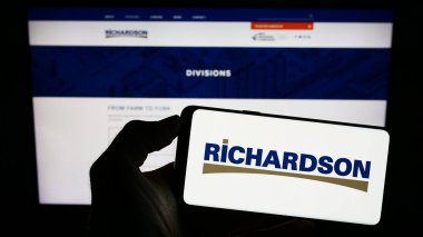 Stuttgart, Almanya - 07-24-2023: Kanadalı şirket Richardson International Limited 'in logosuna sahip akıllı telefon sahibi kişi web sitesinin önünde ekranda. Telefon ekranına odaklan.