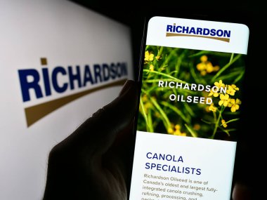Stuttgart, Almanya - 07-24-2023: Kanadalı şirket Richardson International Ltd. 'nin internet sitesiyle cep telefonu tutan kişi logolu ekranda. Telefon ekranının merkezine odaklan.