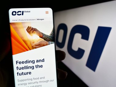 Stuttgart, Almanya - 07-22-2023: Hollandalı kimya şirketi OCI NV 'nin web sayfası ile akıllı telefon sahibi kişi iş logosu önünde ekranda. Telefon ekranının merkezine odaklan.