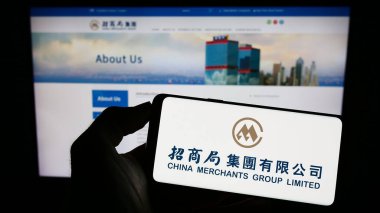 Stuttgart, Almanya - 07-21-2023: Deniz taşımacılığı şirketi China Merchants Group Limited 'in logosunun bulunduğu cep telefonu web sayfası önünde ekranda. Telefon ekranına odaklan.
