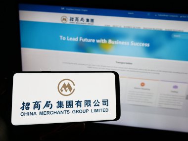 Stuttgart, Almanya - 07-21-2023: Deniz taşımacılığı şirketi China Merchants Group Limited 'in logosunun bulunduğu cep telefonu web sayfası önünde ekranda. Telefon ekranına odaklan.