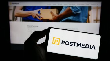 Stuttgart, Almanya - 07-21-2023: İnternet sayfası önünde ekranda, medya şirketi Postmedia Network Canada Corp. 'un logosuyla cep telefonu tutan kişi. Telefon ekranına odaklan.
