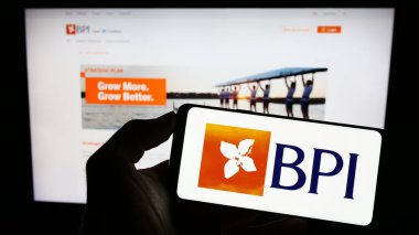 Stuttgart, Almanya - 07-21-2023: İnternet sayfası önünde üzerinde Banco Portugues de Investimento S.A. (BPI) logosu bulunan cep telefonu sahibi kişi. Telefon ekranına odaklan.