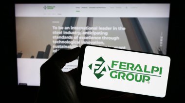 Stuttgart, Almanya - 07-21-2023: İtalyan çelik şirketi Feralpi Group 'un logosunu taşıyan kişi iş sayfasının önünde ekranda. Telefon ekranına odaklan.