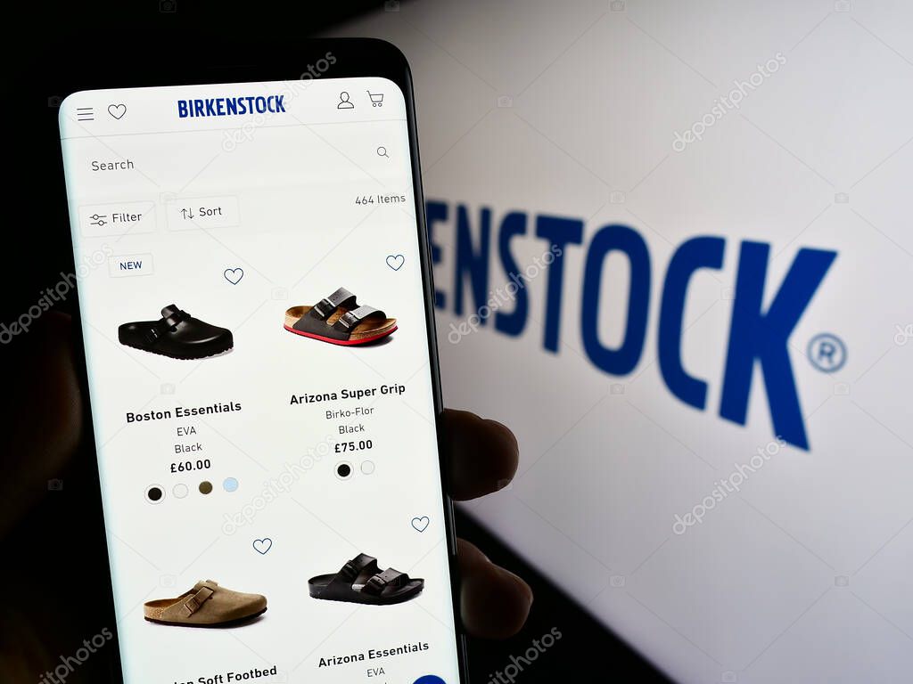 Stuttgart, Germany - 07-24-2023: Person holding cellphone with webpage of shoe company Birkenstock Group B.V. Co. KG on screen in front of logo. Focus on center of phone display.