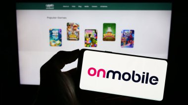 Stuttgart, Almanya - 07-19-2023: Hint şirketi OnMobile Global Limited 'in logosuna sahip akıllı telefon sahibi kişi web sitesinin önünde ekranda. Telefon ekranına odaklan.