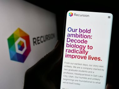 Stuttgart, Almanya - 07-19-2023: ABD 'li şirket Recursion Pharmaceuticals Inc.' in web sitesi ile cep telefonu tutan kişi logonun önünde ekranda. Telefon ekranının merkezine odaklan.