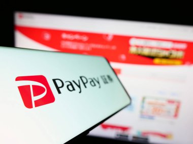 Stuttgart, Almanya - 07-19-2023: Japon ödeme şirketi PayPay Corporation 'ın logosunu içeren cep telefonu iş sitesinin önünde ekranda. Telefon ekranının soluna odaklan.