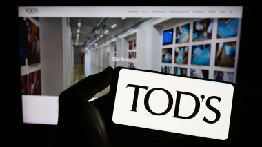 Stuttgart, Almanya - 07-15-2023: İtalyan ayakkabı şirketi Tods S.P.A 'nın logosunu taşıyan kişi web sitesinin önünde ekranda. Telefon ekranına odaklan.