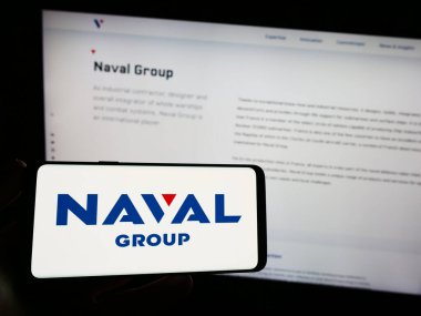 Stuttgart, Almanya - 07-15-2023: Fransız savunma şirketi Naval Group S.A. 'nın logosunu elinde tutan kişi web sitesinin önünde ekranda. Telefon ekranına odaklan.