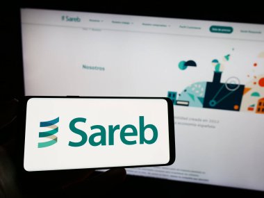 Stuttgart, Almanya - 07-15-2023: İspanyol kötü bankası Sareb 'in logosunun bulunduğu cep telefonu sahibi kişi iş sayfasının önünde ekranda. Telefon ekranına odaklan.
