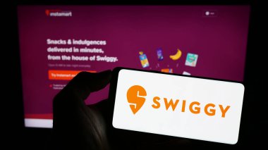 Stuttgart, Almanya - 07-15-2023: Üzerinde Hint gıda dağıtım şirketi Swiggy 'nin logosu olan cep telefonu sahibi kişi iş sayfasının önünde ekranda. Telefon ekranına odaklan.