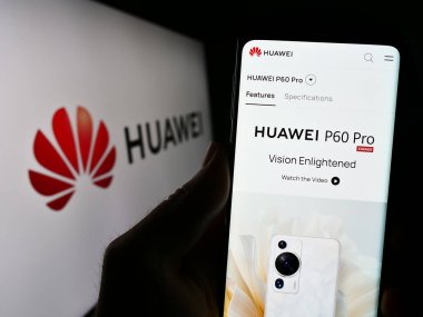 Stuttgart, Almanya - 07-15-2023: Çinli Huawei Technologies Co. Ltd. şirketinin web sitesi ile cep telefonu tutan kişi logolu ekranda. Telefon ekranının merkezine odaklan.