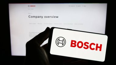 Stuttgart, Almanya - 07-15-2023: Alman mühendislik şirketi Robert Bosch GmbH 'nin logosunu elinde tutan kişi web sitesinin önünde ekranda. Telefon ekranına odaklan.