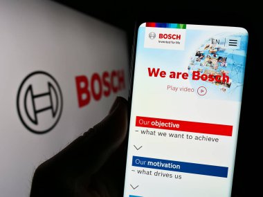 Stuttgart, Almanya - 07-15-2023: Alman mühendislik şirketi Robert Bosch GmbH 'nin web sitesi ile akıllı telefonu elinde tutan kişi logolu ekranda. Telefon ekranının merkezine odaklan.