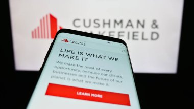 Stuttgart, Almanya - 07-15-2023: Emlak şirketi Cushman Wakefield plc 'in web sitesiyle birlikte cep telefonu iş logosu önünde ekranda. Telefon ekranının sol üst kısmına odaklan.