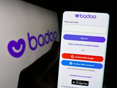 Stuttgart, Almanya - 07-15-2023: Logo önünde ekranda Badoo (Bumble Inc.) flört platformu web sitesi bulunan cep telefonu sahibi kişi. Telefon ekranının merkezine odaklan.