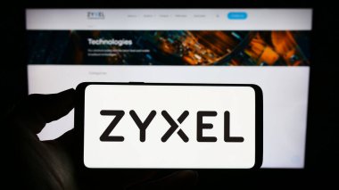 Stuttgart, Almanya - 07-14-2023: Zyxel Communications Corporation şirketinin logosuna sahip cep telefonu sahibi kişi iş sayfasının önünde ekranda. Telefon ekranına odaklan.