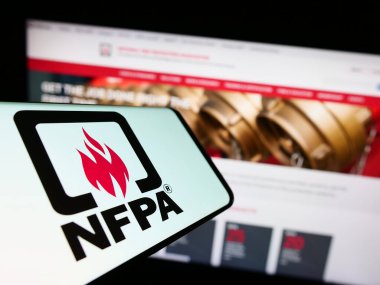 Stuttgart, Germany - 07-13-2023: Smartphone with logo of National Fire Protection Association (NFPA) on screen in front of website. Focus on center-right of phone display. clipart