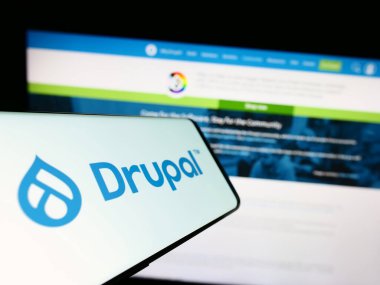 Stuttgart, Almanya - 07-13-2023: İnternet sitesi önünde ekranda Drupal içerik yönetim sisteminin logosuna sahip cep telefonu. Telefon ekranının merkezine odaklan.