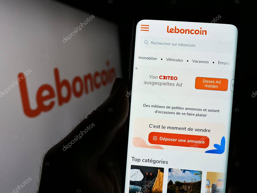 Stuttgart, Germany - 07-13-2023: Person holding cellphoe with webpage of French classified ads company Leboncoin on screen in front of logo. Focus on center of phone display.