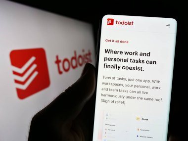 Stuttgart, Almanya - 07-12-2023: ABD 'li iş yönetimi şirketi Todoist' in (Doist Inc.) web sitesi ile cep telefonu tutan kişi logo ile ekranda. Telefon ekranının merkezine odaklan.