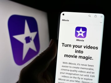 Stuttgart, Almanya - 07-12-2023: Logo önünde ekranda video düzenleme yazılımı iMovie (Apple Inc.) web sitesi bulunan cep telefonu sahibi kişi. Telefon ekranının merkezine odaklan.