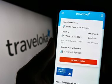 Stuttgart, Almanya - 07-12-2023: Endonezyalı seyahat şirketi Traveloka 'nın internet sayfası ile logo önünde cep telefonu tutan kişi. Telefon ekranının merkezine odaklan.