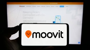 Stuttgart, Almanya - 07-12-2023: İsrailli hareketlilik şirketi Moovit Inc. 'in logosunu taşıyan cep telefonu sahibi kişi iş sayfasının önünde ekranda. Telefon ekranına odaklan.