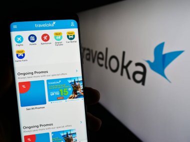 Stuttgart, Almanya - 07-12-2023: Endonezyalı seyahat şirketi Traveloka 'nın web sayfası ile logo önünde akıllı telefon tutan kişi. Telefon ekranının merkezine odaklan.