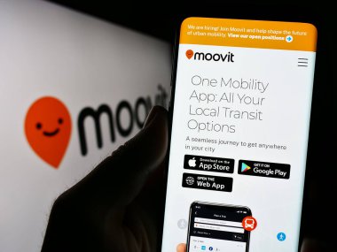 Stuttgart, Almanya - 07-12-2023: İsrailli Mobilite Şirketi Moovit Inc. 'in web sayfası ile logo önünde cep telefonu tutan kişi. Telefon ekranının merkezine odaklan.