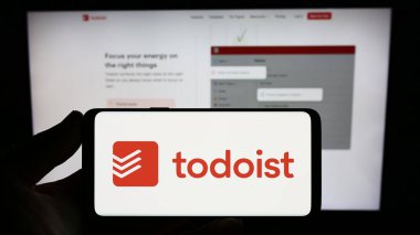 Stuttgart, Almanya - 07-12-2023: İnternet sitesi önünde üzerinde ABD 'li görev şirketi Todoist' in logosu olan akıllı telefon sahibi kişi. Telefon ekranına odaklan.