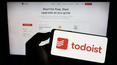Stuttgart, Almanya - 07-12-2023: İnternet sayfası önünde ABD 'li iş yönetimi şirketi Todoist' in (Doist Inc.) logosuyla cep telefonu tutan kişi. Telefon ekranına odaklan.