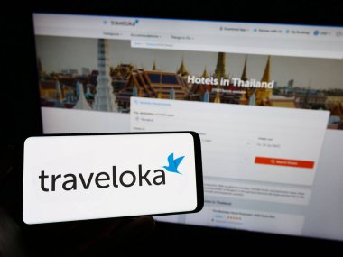 Stuttgart, Almanya - 07-12-2023: Endonezyalı seyahat şirketi Traveloka 'nın logosunun bulunduğu cep telefonu sahibi kişi iş sayfasının önünde ekranda. Telefon ekranına odaklan.