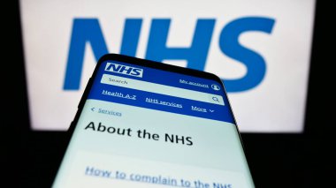 Stuttgart, Almanya - 07-12-2023: Logo önünde ekranda İngiliz Ulusal Sağlık Servisi (NHS) web sitesi bulunan cep telefonu. Telefon ekranının sol üst kısmına odaklan.
