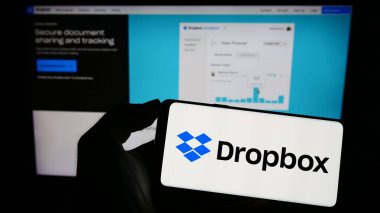 Stuttgart, Almanya - 07-11-2023: ABD dosya sunucu şirketi Dropbox Inc. 'in logosuyla cep telefonu sahibi kişi iş sayfasının önünde ekranda. Telefon ekranına odaklan.