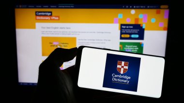 Stuttgart, Almanya - 07-11-2023: Cep telefonunda Cambridge Sözlüğü logosu olan kişi web sayfasının önünde ekranda. Telefon ekranına odaklan.