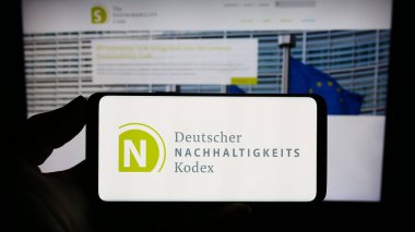 Stuttgart, Almanya - 07-11-2023: İnternet sitesi önünde üzerinde Deutscher Nachhaltigkeitskodex (DNK) logosu bulunan kişi. Telefon ekranına odaklan.