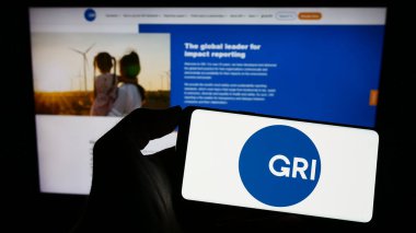 Stuttgart, Almanya - 07-11-2023: Web sayfası önünde Global Reporting Initiative (GRI) logosu olan cep telefonu sahibi kişi. Telefon ekranına odaklan.