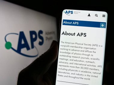 Stuttgart, Almanya - 07-09-2023: Amerikan Fizik Toplumu (APS) adlı Amerikan örgütünün internet sayfası ile cep telefonu tutan kişi logolu ekranda. Telefon ekranının merkezine odaklan.