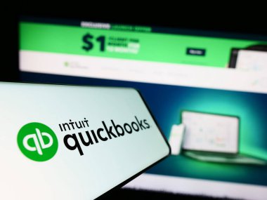Stuttgart, Almanya - 07-09-2023: İş dünyasının web sitesinin önündeki ekranda muhasebe yazılımı QuickBooks logosu olan cep telefonu. Telefon ekranının merkez soluna odaklan.