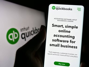 Stuttgart, Almanya - 07-09-2023: Logo önündeki ekranda, muhasebe yazılımı QuickBooks web sayfası ile cep telefonu tutan kişi. Telefon ekranının merkezine odaklan.