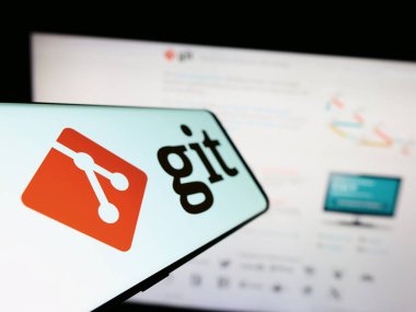 Stuttgart, Almanya - 07-09-2023: İnternet sitesinin önündeki ekranda dağıtılmış sürüm kontrol sistemi git logosuna sahip cep telefonu. Telefon ekranının soluna odaklan.