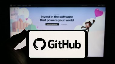 Stuttgart, Almanya - 07-09-2023: İnternet sitesinin önünde ekranda ABD 'li yazılım geliştirme şirketi GitHub Inc.' in logosuna sahip akıllı telefonu tutan kişi. Telefon ekranına odaklan.