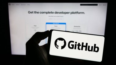 Stuttgart, Almanya - 07-09-2023: ABD 'li yazılım geliştirme şirketi GitHub Inc.' in logosuyla cep telefonu sahibi kişi iş sayfasının önünde ekranda. Telefon ekranına odaklan.
