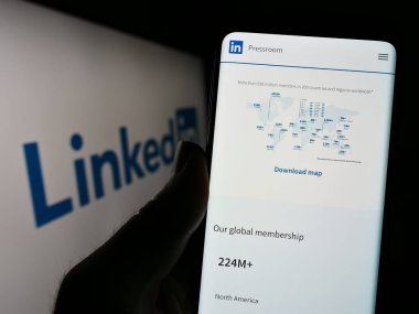 Stuttgart, Almanya - 07-09-2023: ABD 'li sosyal medya şirketi LinkedIn Corporation' ın internet sayfası ile cep telefonu tutan kişi logolu ekranda. Telefon ekranının merkezine odaklan.
