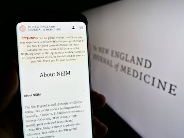 Stuttgart, Almanya - 07-09-2023: The New England Journal of Medicine (NEJM) sitesinin logolu cep telefonunu elinde tutan kişi. Telefon ekranının merkezine odaklan.