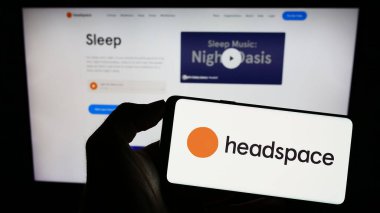 Stuttgart, Almanya - 07-09-2023: Meditasyon şirketi Headspace Inc. 'nin logosuyla cep telefonu sahibi olan kişi iş sayfasının önünde ekranda. Telefon ekranına odaklan.