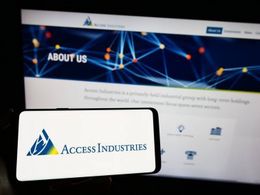 Stuttgart, Almanya - 07-08-2023: ABD holding şirketi Access Industries Inc. 'in logosunu elinde tutan kişi web sitesinin önünde ekranda. Telefon ekranına odaklan.